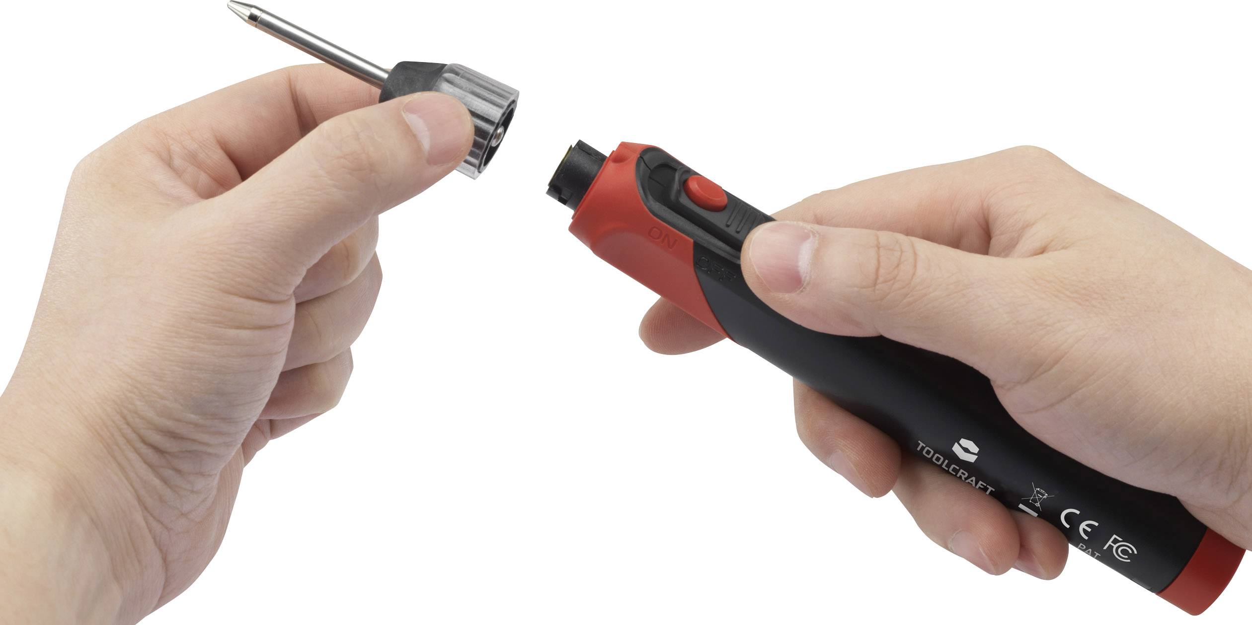 A person is holding a black and red screwdriver with a removable bit in their hand.