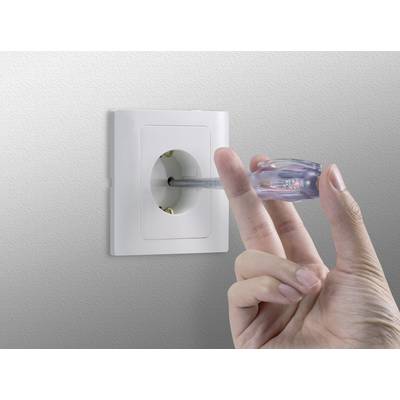 A hand is holding a voltage tester that is plugged into a wall socket.