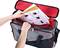A person is placing documents into an open grey and red bag. The documents display product images and descriptions.