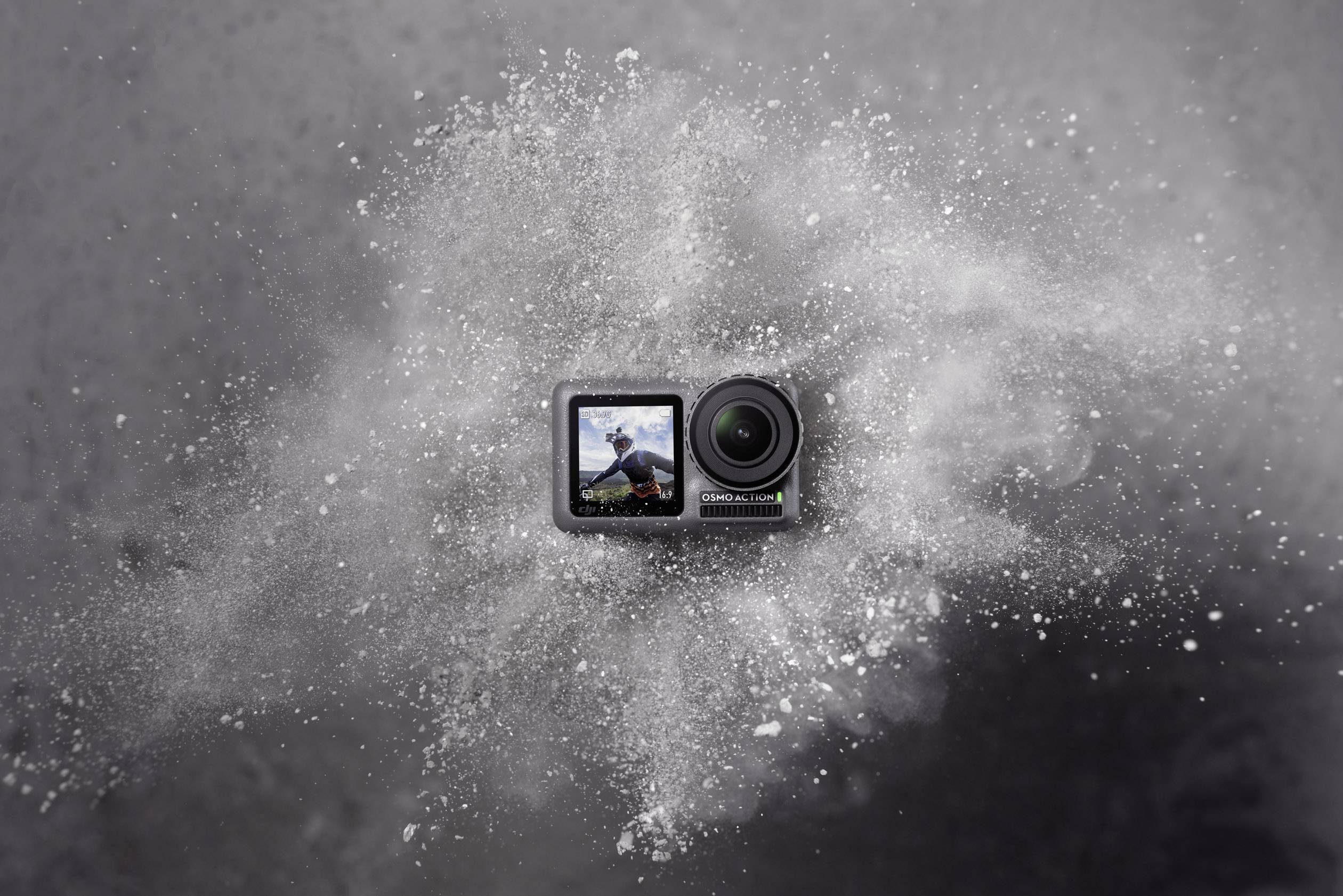 An action camera on a grey background, with an image of a surfer on the display.