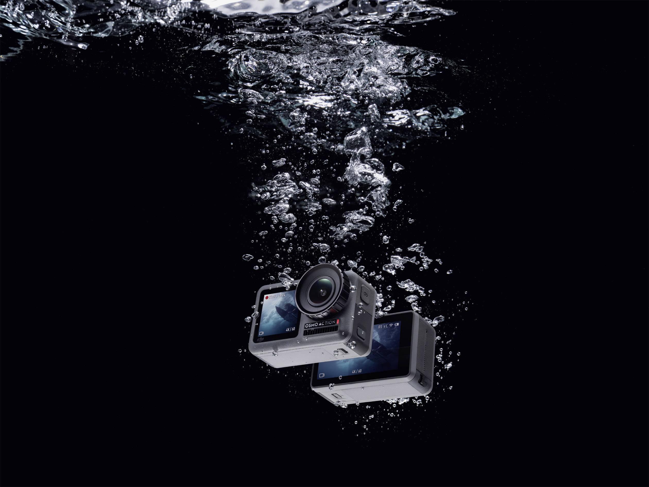A camera with a screen is submerged and surrounded by air bubbles, indicating its waterproof capability.