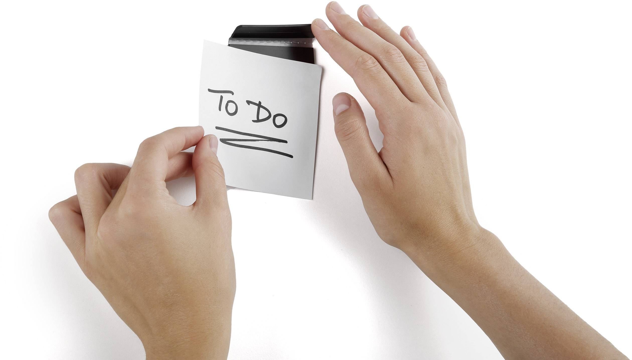 Two hands are attaching a note with the inscription 'To Do' to a black clip.