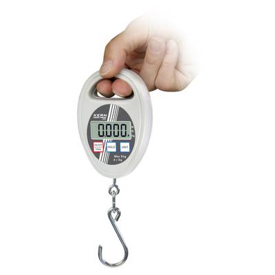 A hand holds a digital luggage scale with a hook. The display shows '0.000'. Buttons for tare, hold, and units are located beneath the display.