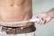A man measures his waist circumference with a tape measure to check his health status.