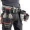 A tool belt with multiple pockets, filled with screwdrivers and other tools, is worn by a worker around the waist.