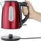 A red kettle is being held by a hand. The base with power cable is shown separately at the bottom of the image.