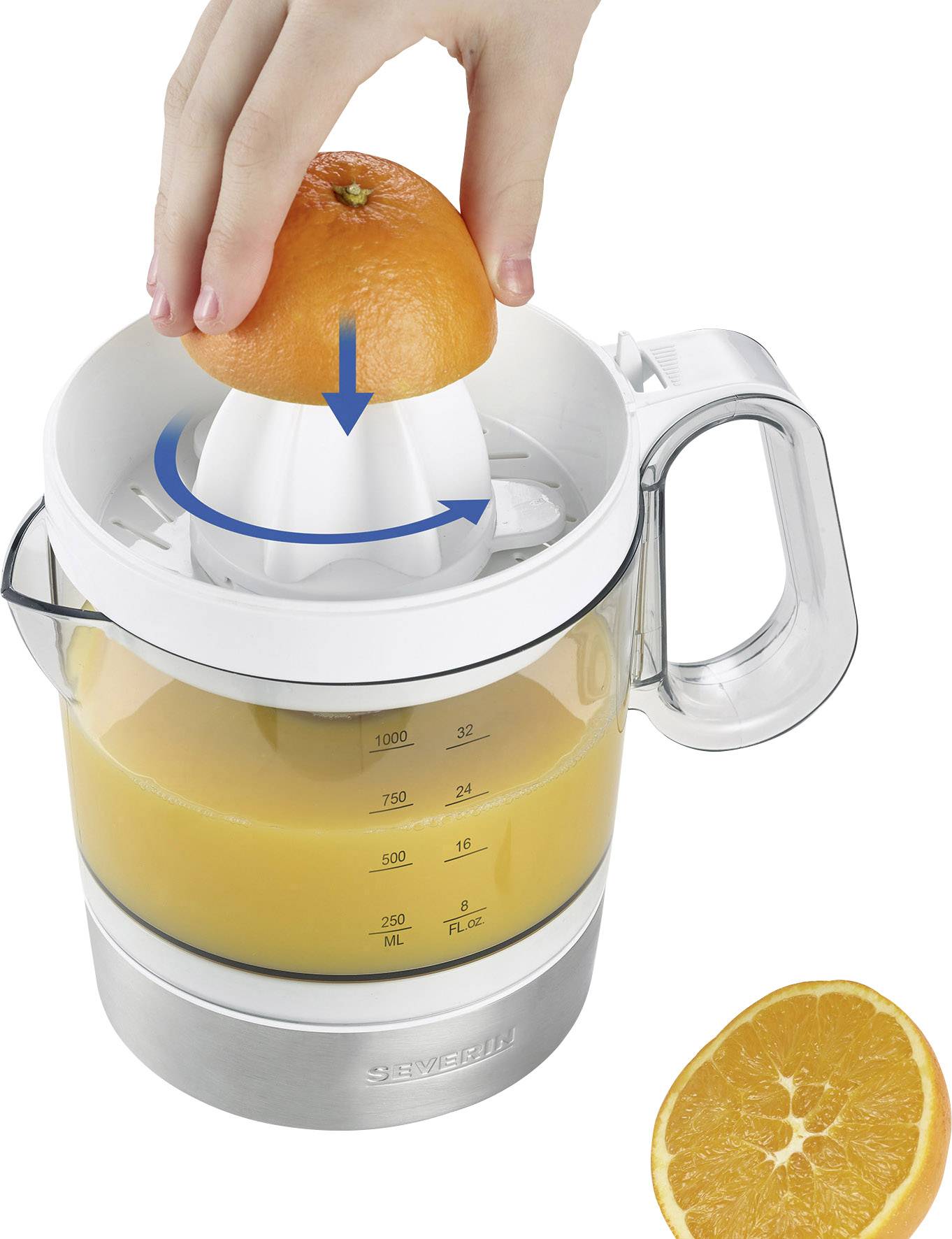 A hand presses half an orange onto an electric juicer. A jug beneath it is almost full of orange juice. A half orange lies beside it.