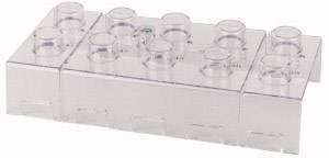 A transparent plastic building block in a brick design, similar to a LEGO brick, with six round studs on the top surface.