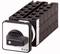 Black rotary switch with a square silver front plate, mounted on a black modular system. Brand 'Eaton'.