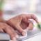 A hand inserts a white cleaning wipe into an electronic device to clean it. The focus is on cleanliness and hygiene.