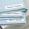 Three blue ring binders with labels: 'Andrews R. - Evaluation', 'Chambers J. - Evaluation', 'Black G. - Evaluation', on a table.