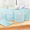 Five pale blue gift bags with hyacinths inside are standing on a wooden table in front of a window.