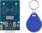 An RFID reader with a blue RFID chip card. The reader is electronic, and the card has a key fob.