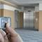A hand is holding a remote control in a building, with a lift visible in the background.
