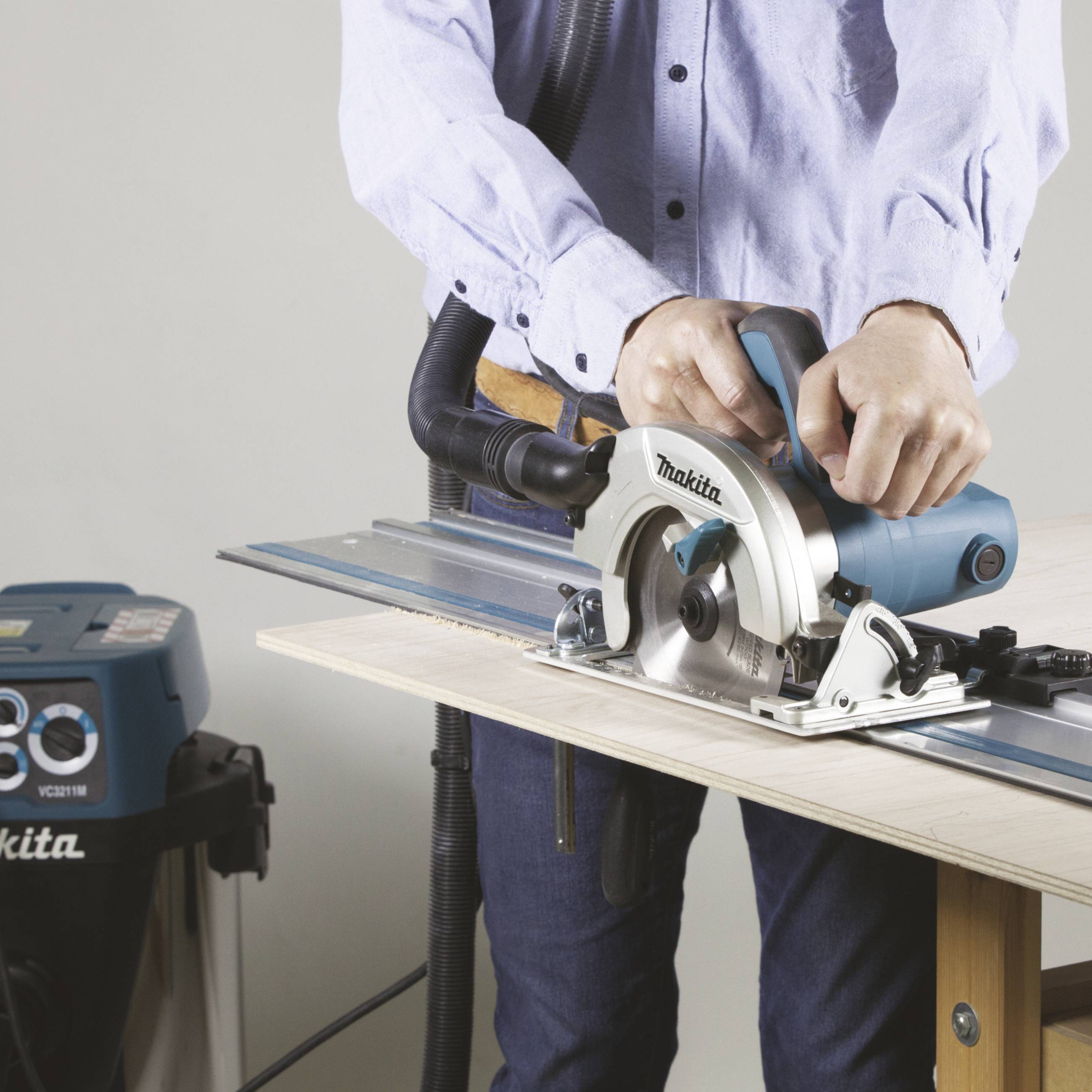 A person is using a handheld circular saw to cut a board. The tool is a Makita brand and demonstrates precise workmanship.