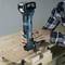 A person is working with a blue cordless drill on a piece of wood on a workbench.