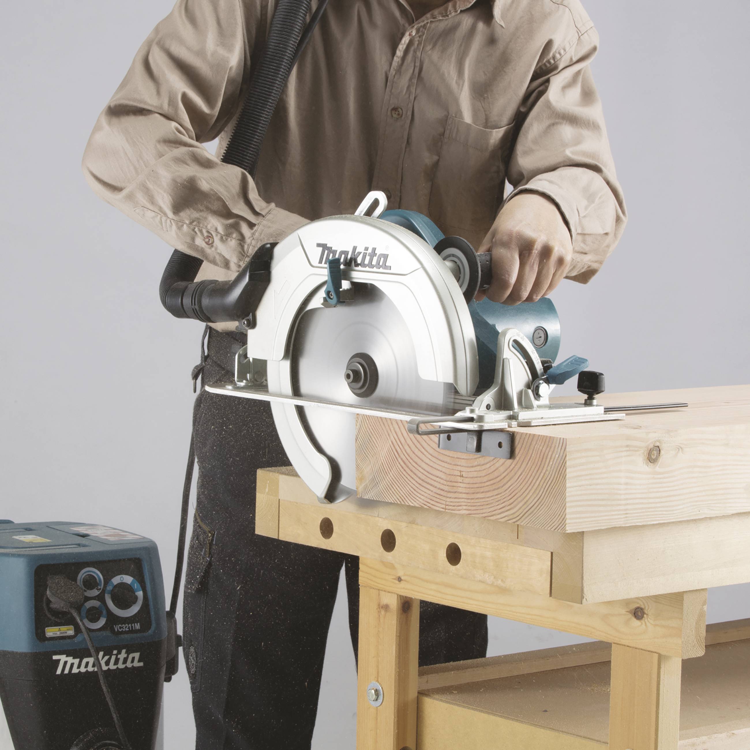 A person is operating a circular saw to cut a piece of wood. The saw is mounted on a sturdy wooden table.