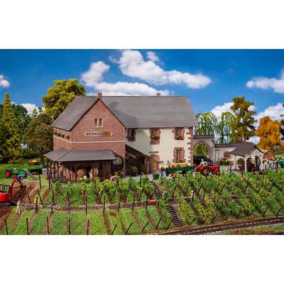 A miniature model depicts a wine cellar with vineyards and tractors beneath a blue sky with white clouds.