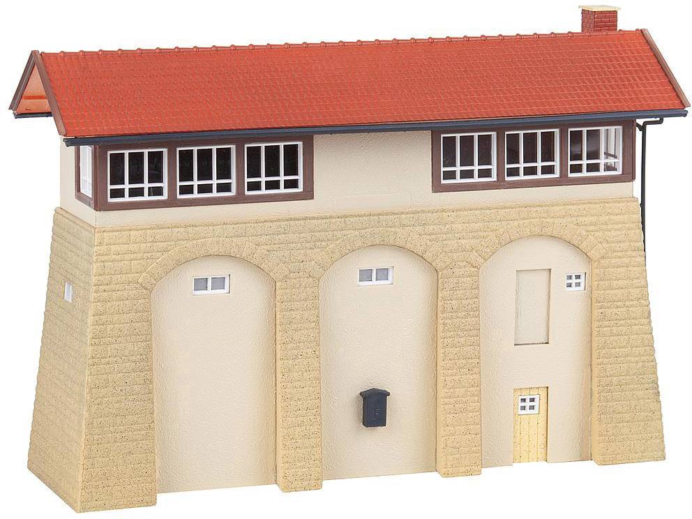 A beige model building with a red pitched roof, windows, and a door. It has a brick structure with arches on the front.