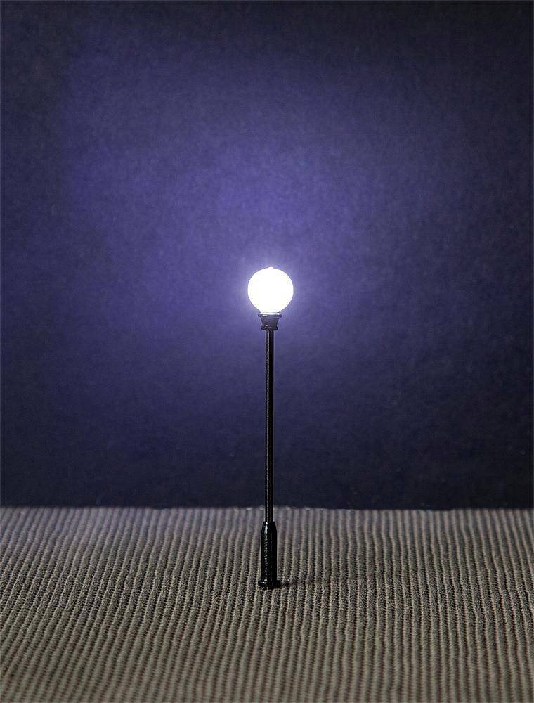 A small street lamp illuminates against a blue background over a textured surface.