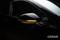 Side wing mirror of a car with an activated flashing indicator.