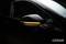 A black car wing mirror with an illuminated, orange indicator light.