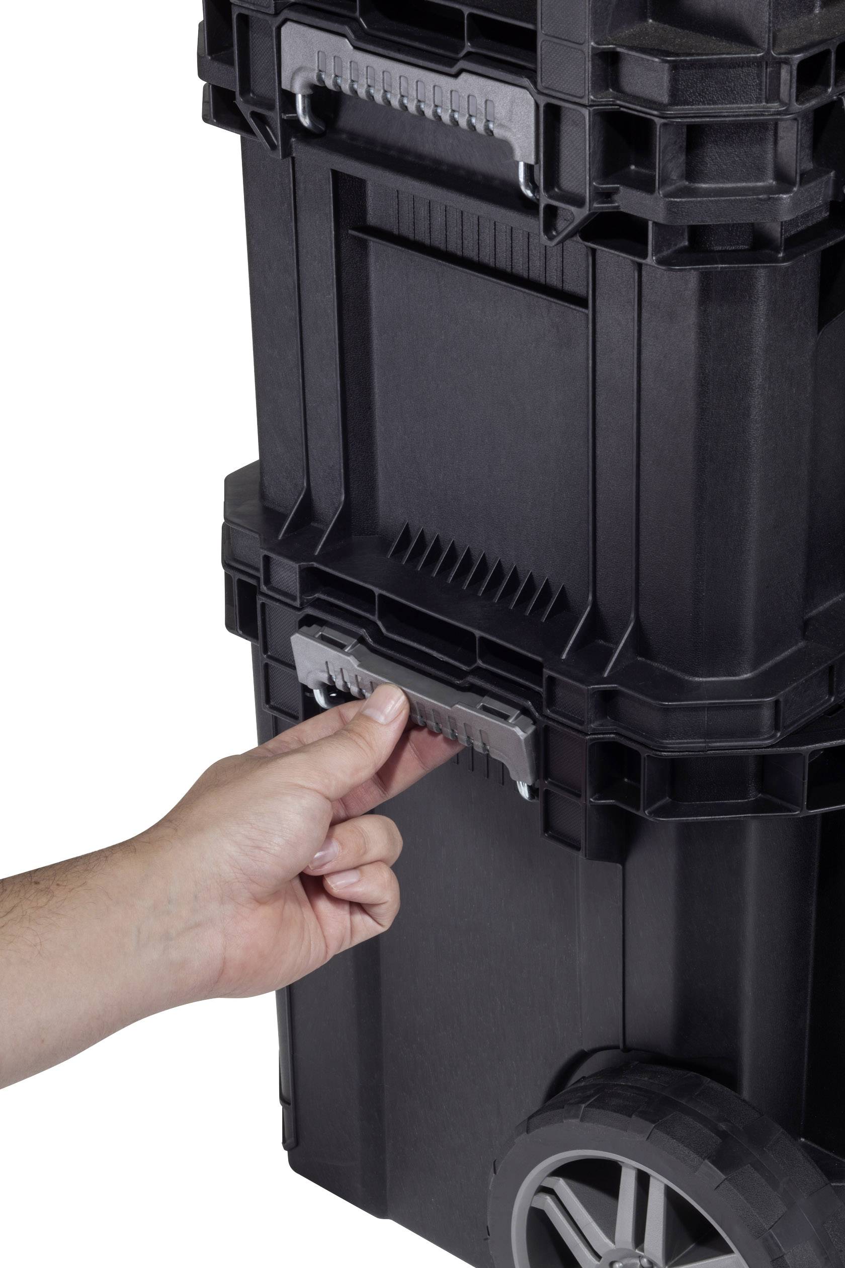 A hand grasps the handle of a stackable, black tool case system with wheels.