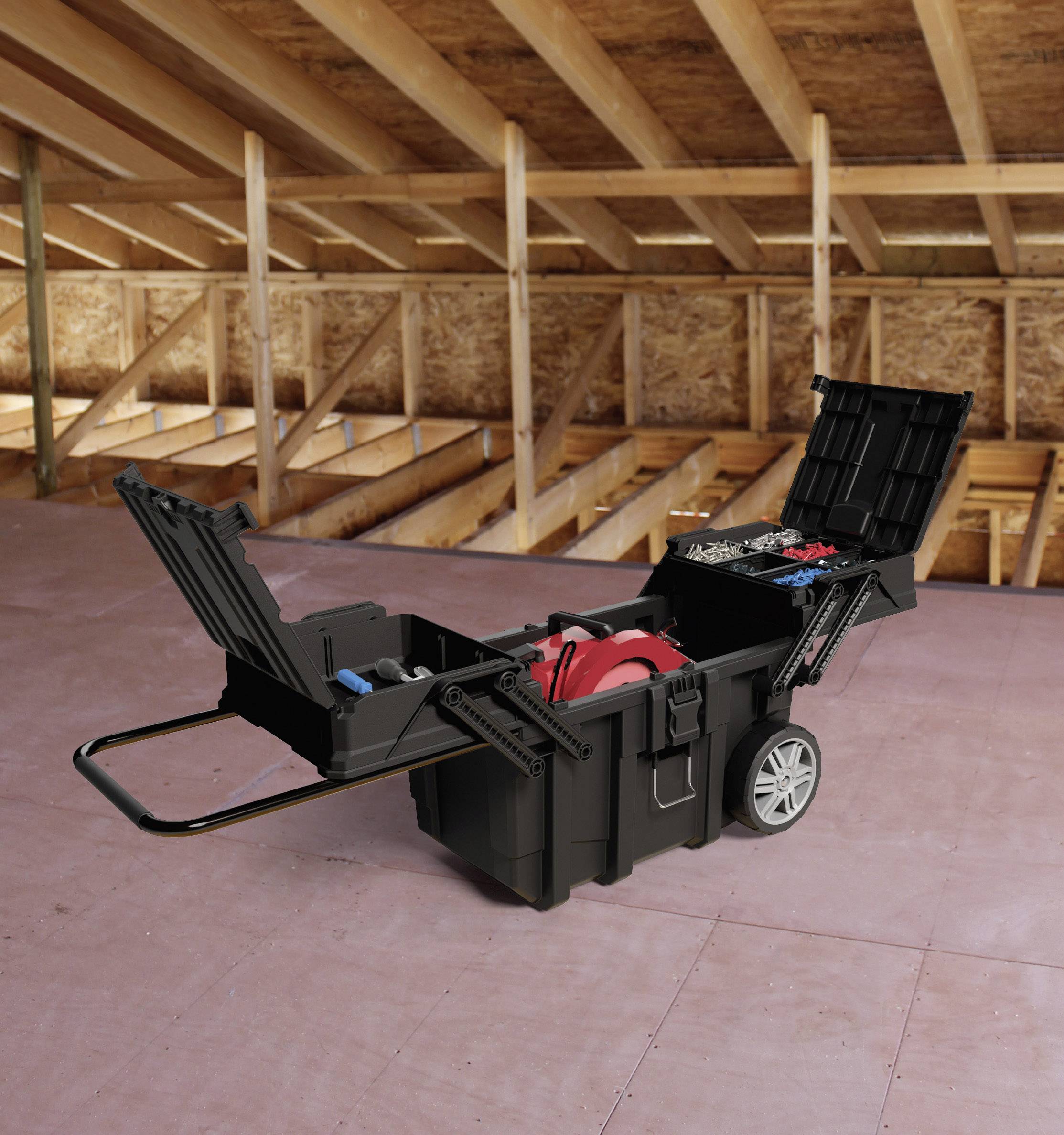 An opened black toolbox with wheels in an attic. The box is filled with various tools.