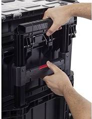 Two hands lift a black, stacked toolbox with handles.