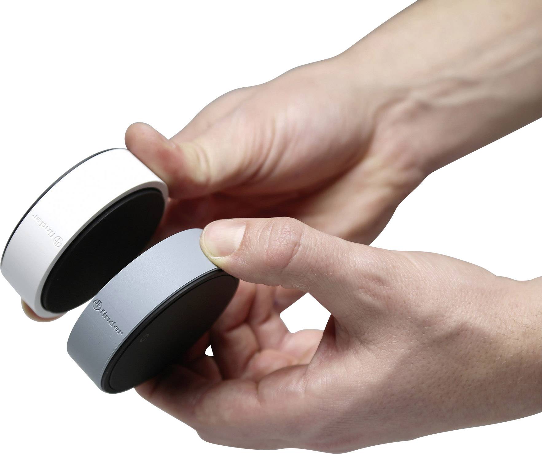 Two hands are holding two round, flat devices, one white, the other grey. Both devices are printed with the brand logo.