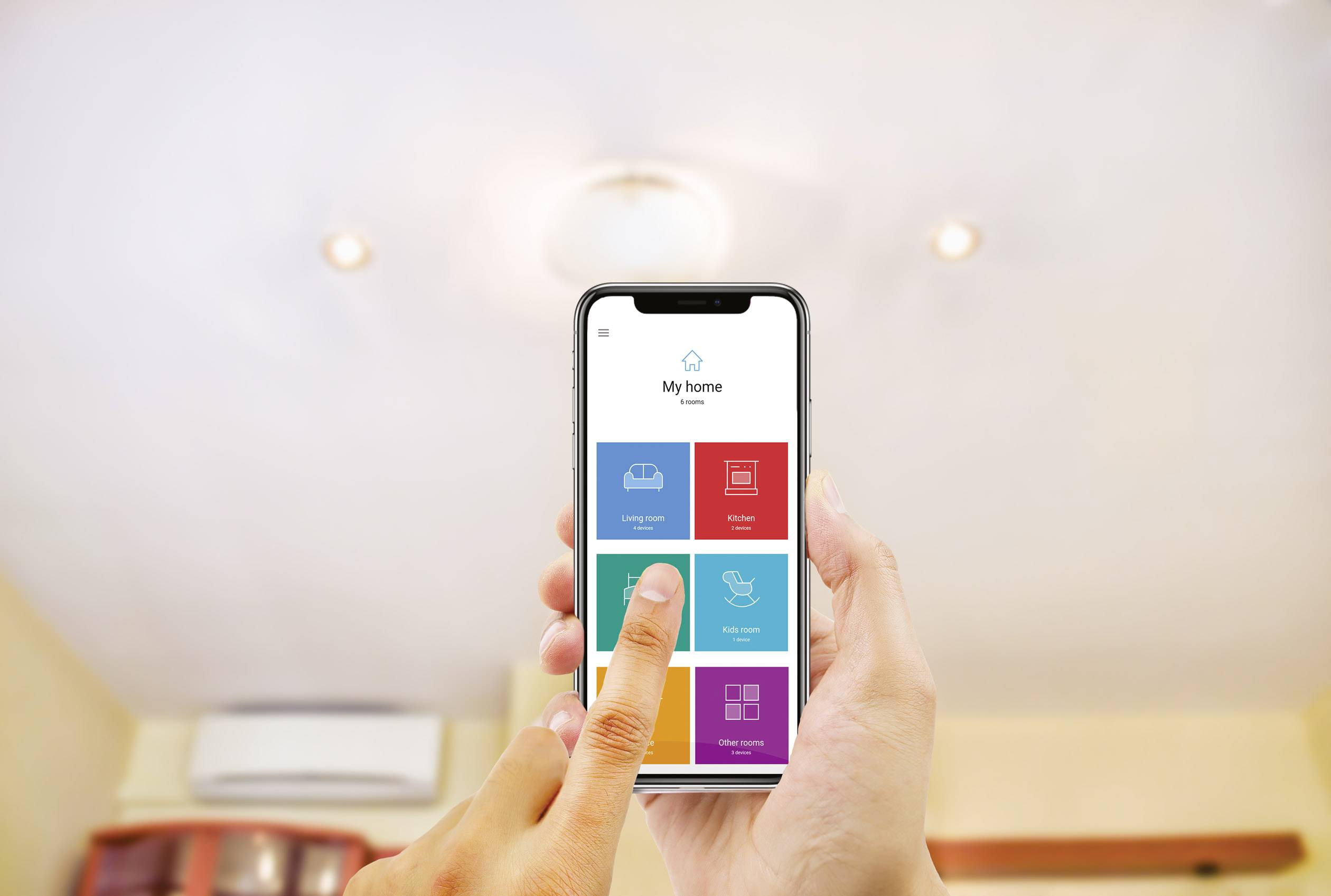 A person is using a smart home app on a smartphone to control the light in a room with a ceiling light.