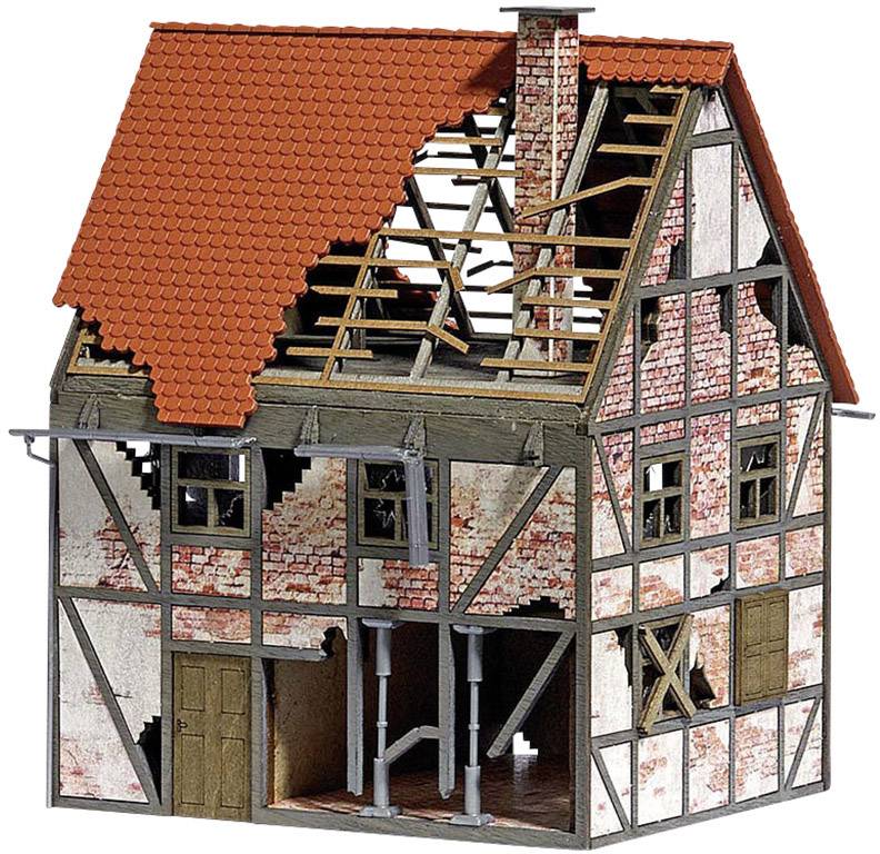 A miniature model of a half-timbered house with a partially destroyed roof and damaged walls, revealing visible bricks and wooden beams.