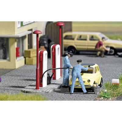 Two miniature figures are filling up a yellow car at a petrol station. Another vehicle with one person is visible in the background.