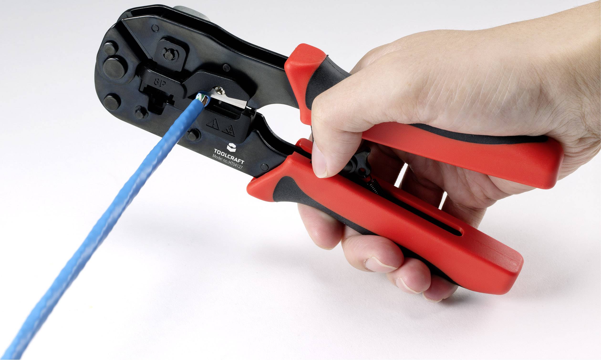 'Close-up of a hand holding a crimping tool and working on a blue cable, against a white background.'