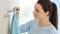A woman hangs a blue towel on a hook on the wall.