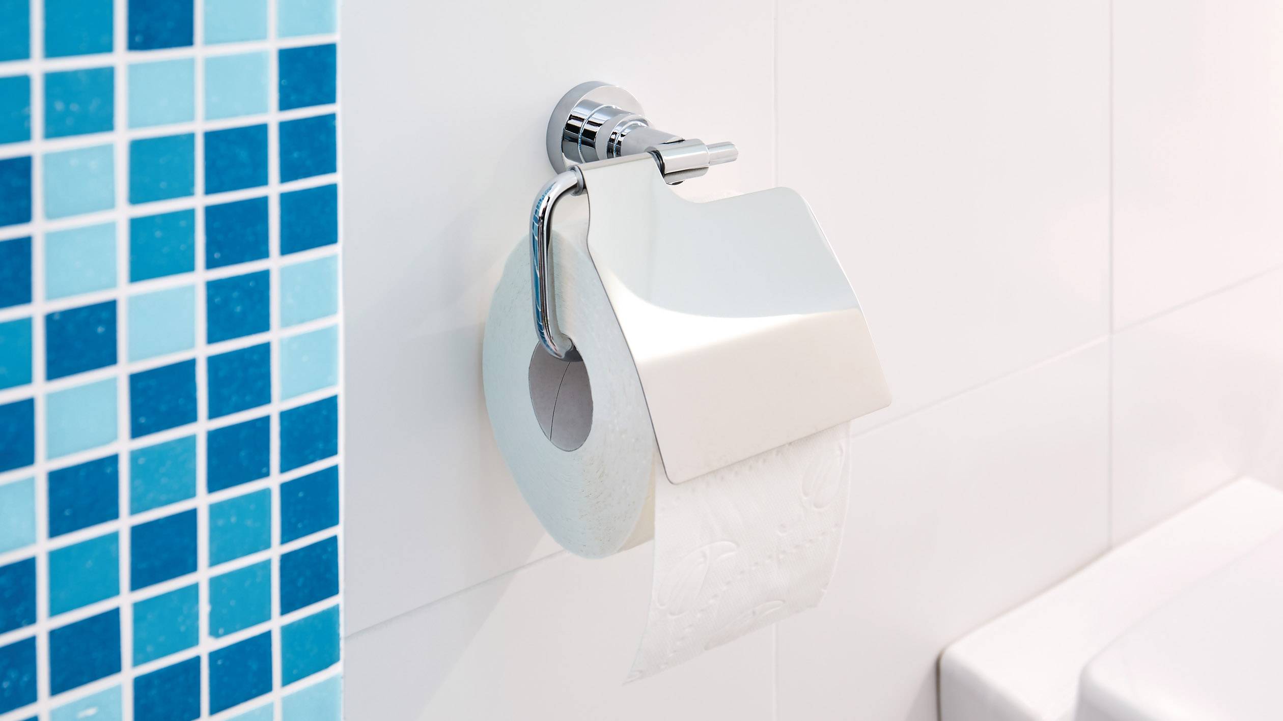 Toilet roll hanging on a holder against a tiled bathroom wall.