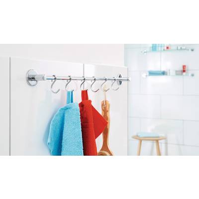 Towels and a brush hang on hooks from a metal rail in a modern bathroom with white-tiled walls and a shelf in the background.