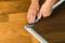 A person is installing an insect screen with a metal frame on a wooden floor by fitting the mesh into the frame.