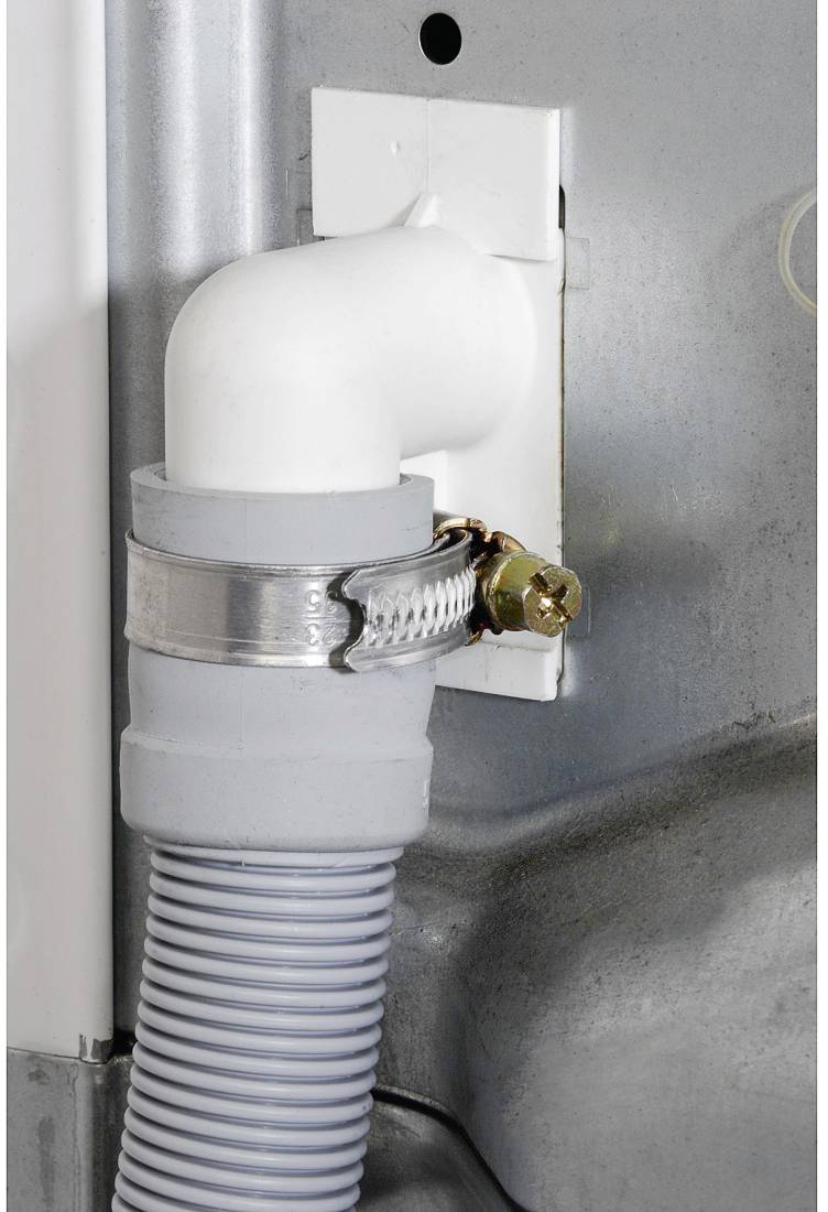 Grey drain hose pipe with metal clip fastened, connecting household appliance to water connection on the wall.