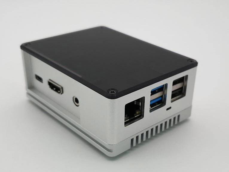 A silver and black computer case with multiple USB, Ethernet, and HDMI ports on a white surface.