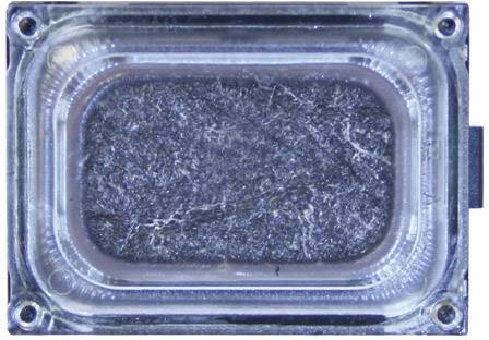 The image shows a rectangular speaker in close-up, surrounded by a transparent plastic enclosure.