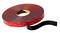 A roll of double-sided adhesive tape with a red protective strip and black adhesive side, ideal for strong bonds.