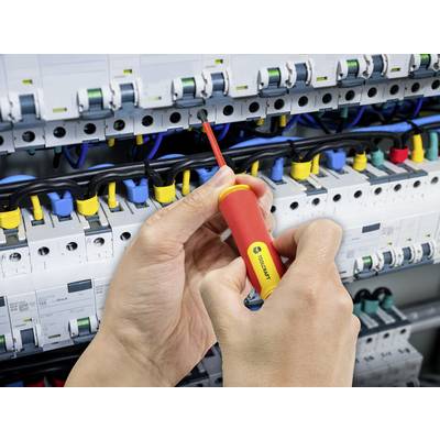 A person is using a screwdriver to connect cables to an electrical control panel. Various coloured cables are visible.