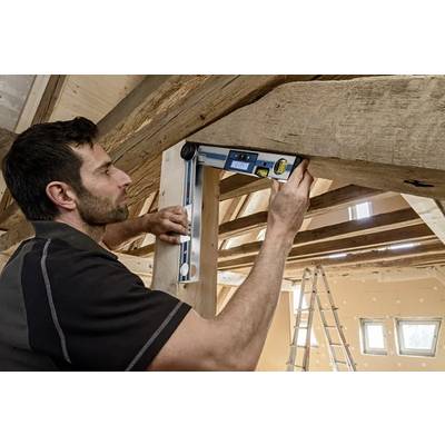 A person uses a digital angle finder on a wooden beam in a partially constructed room, indicating precision in carpentry work.