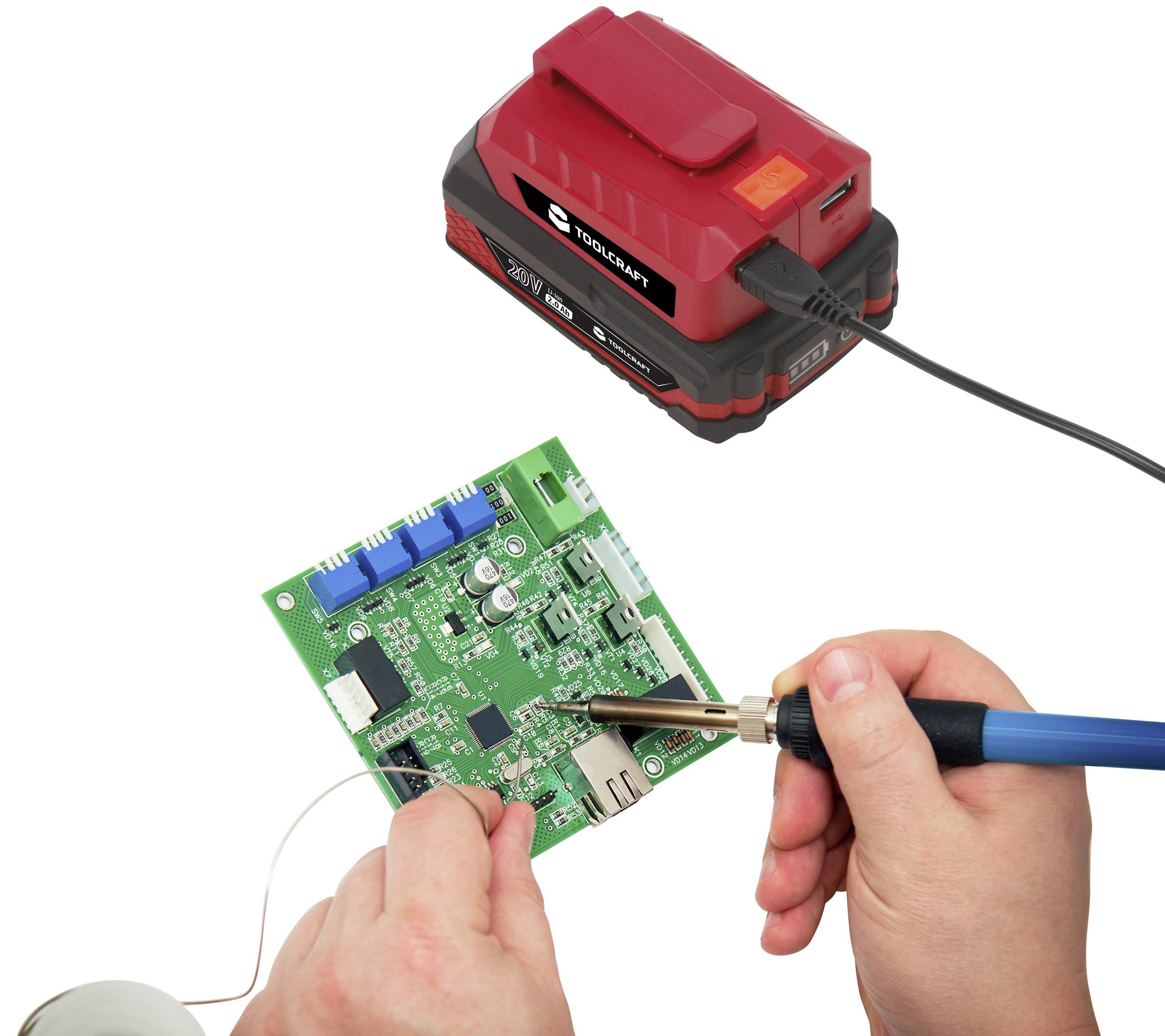 'A person is soldering a green circuit board that is connected to a red charger. Technology and repair in focus.'