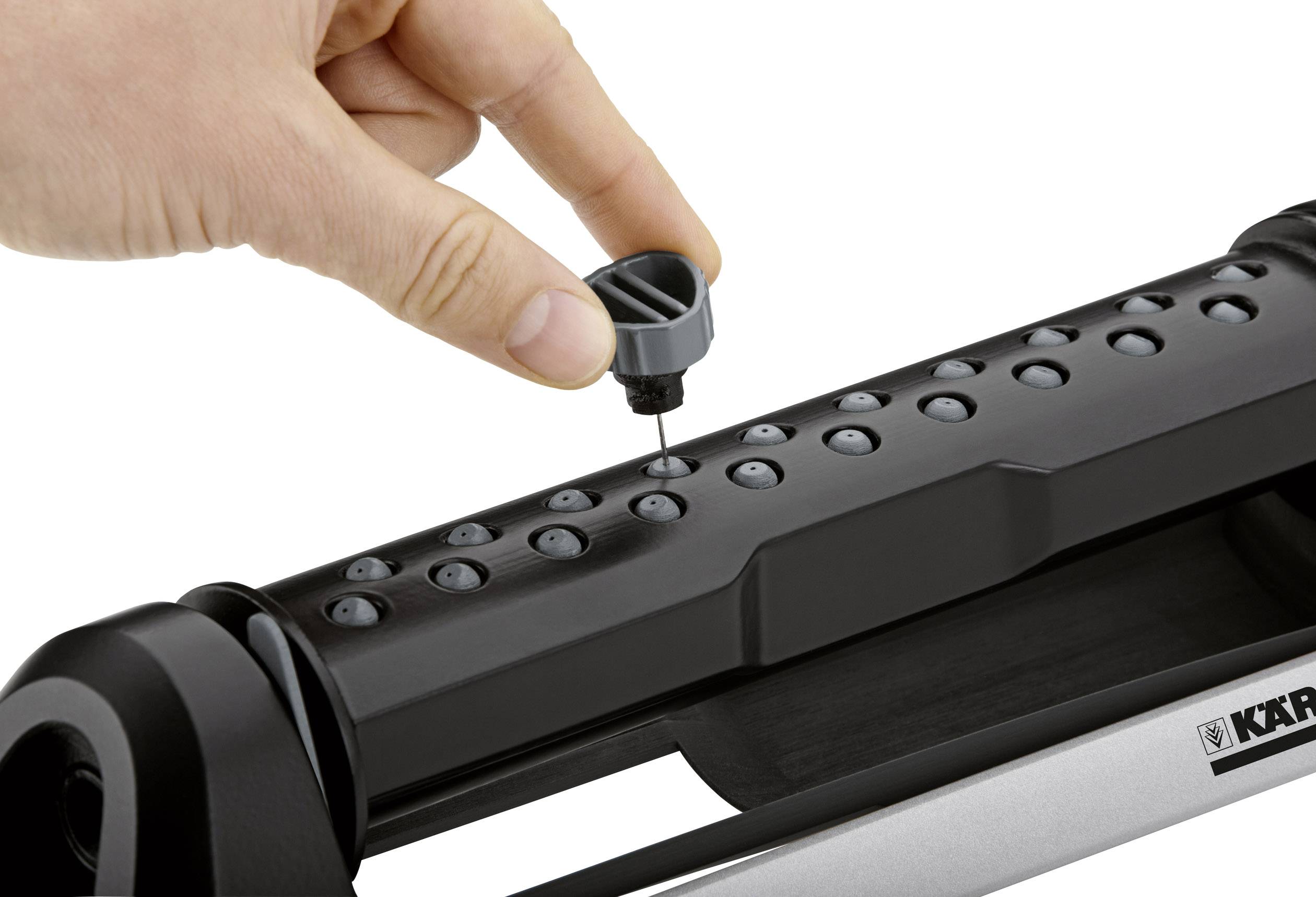 A hand adjusts the water flow of a black garden sprinkler with a rotary dial.