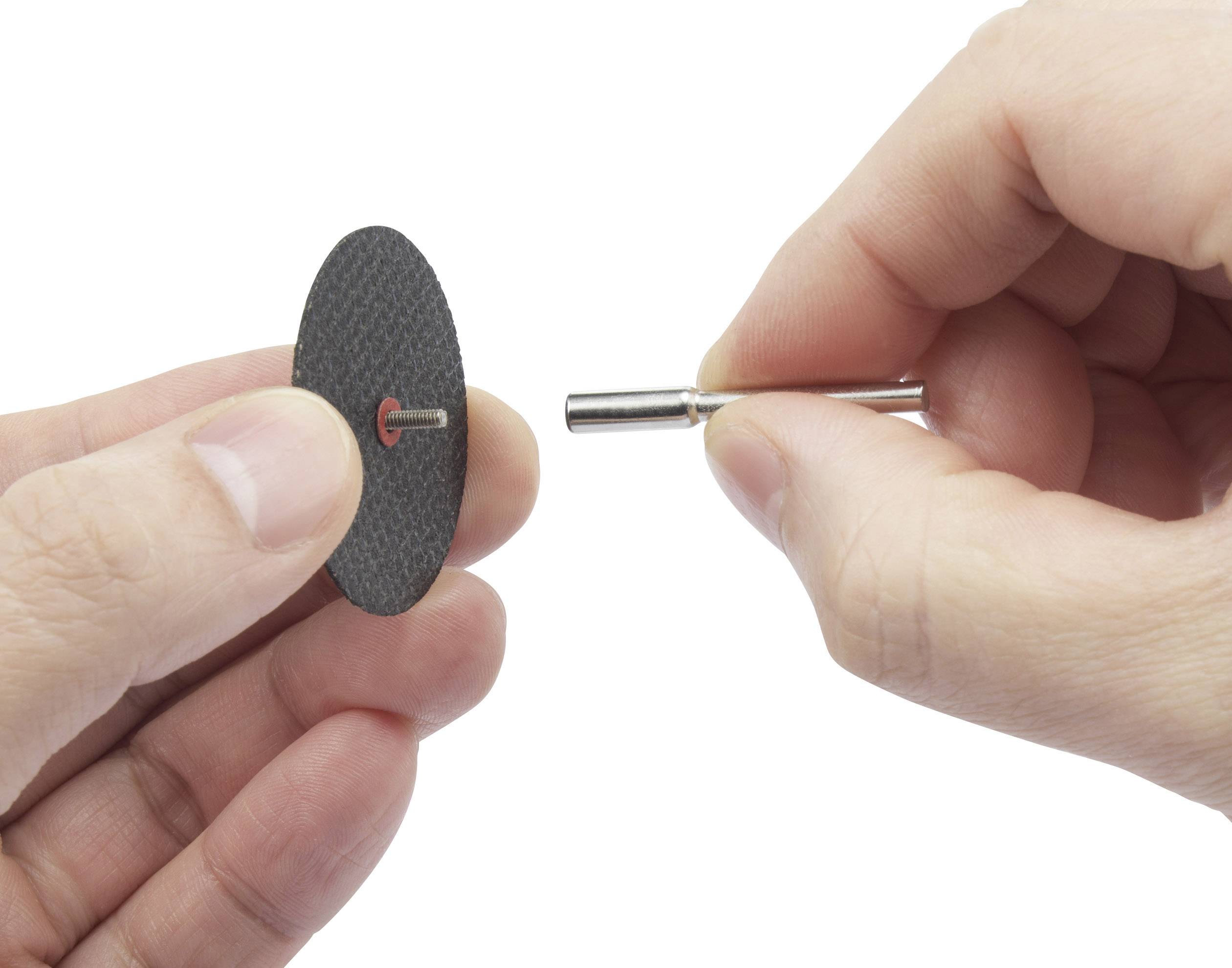 Two hands are holding a small cutting disc and a Dremel drill. The cutting disc is ready to be attached to the drill.