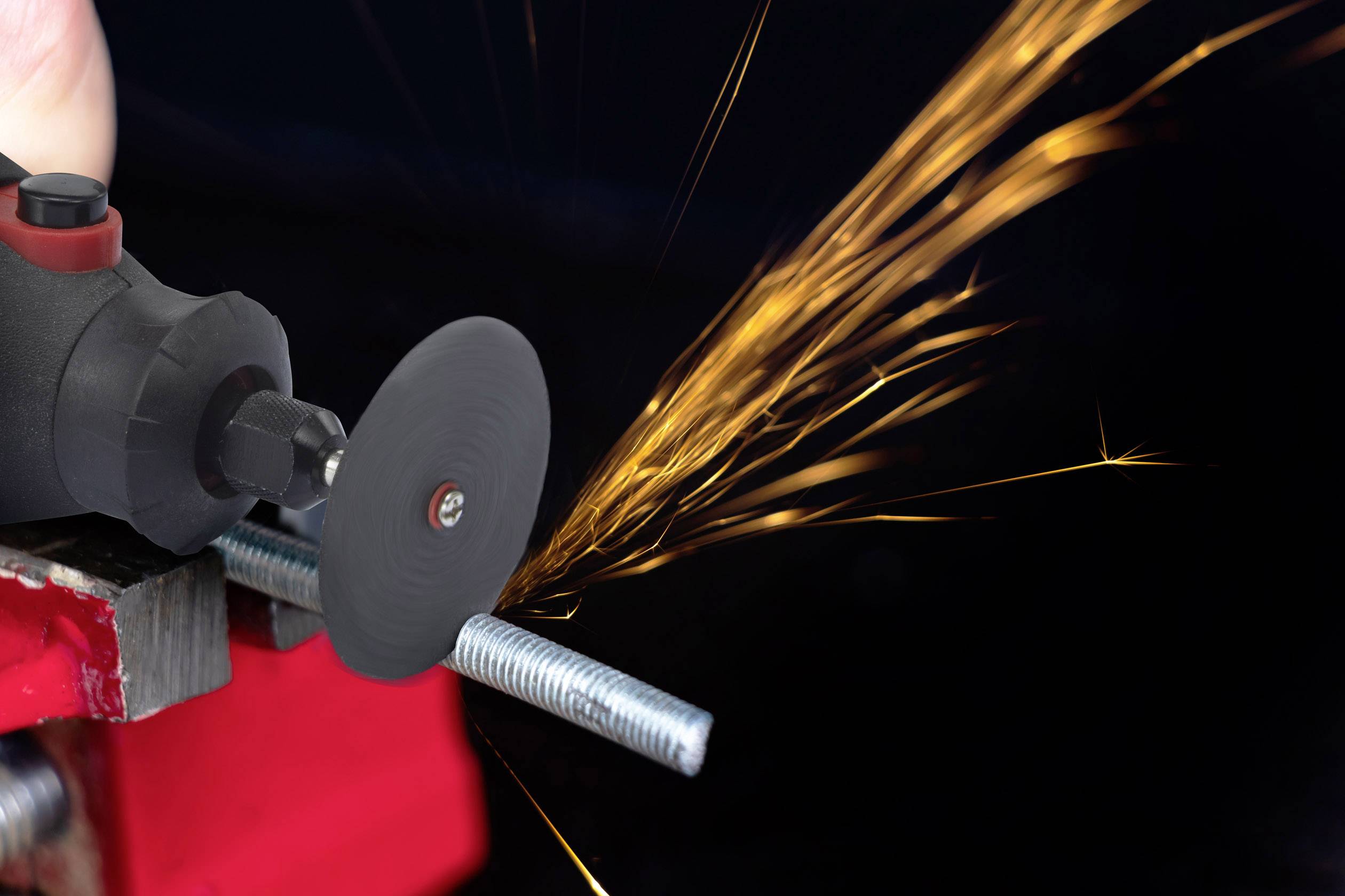 An electric cutting disc severs a metal rod as sparks fly.