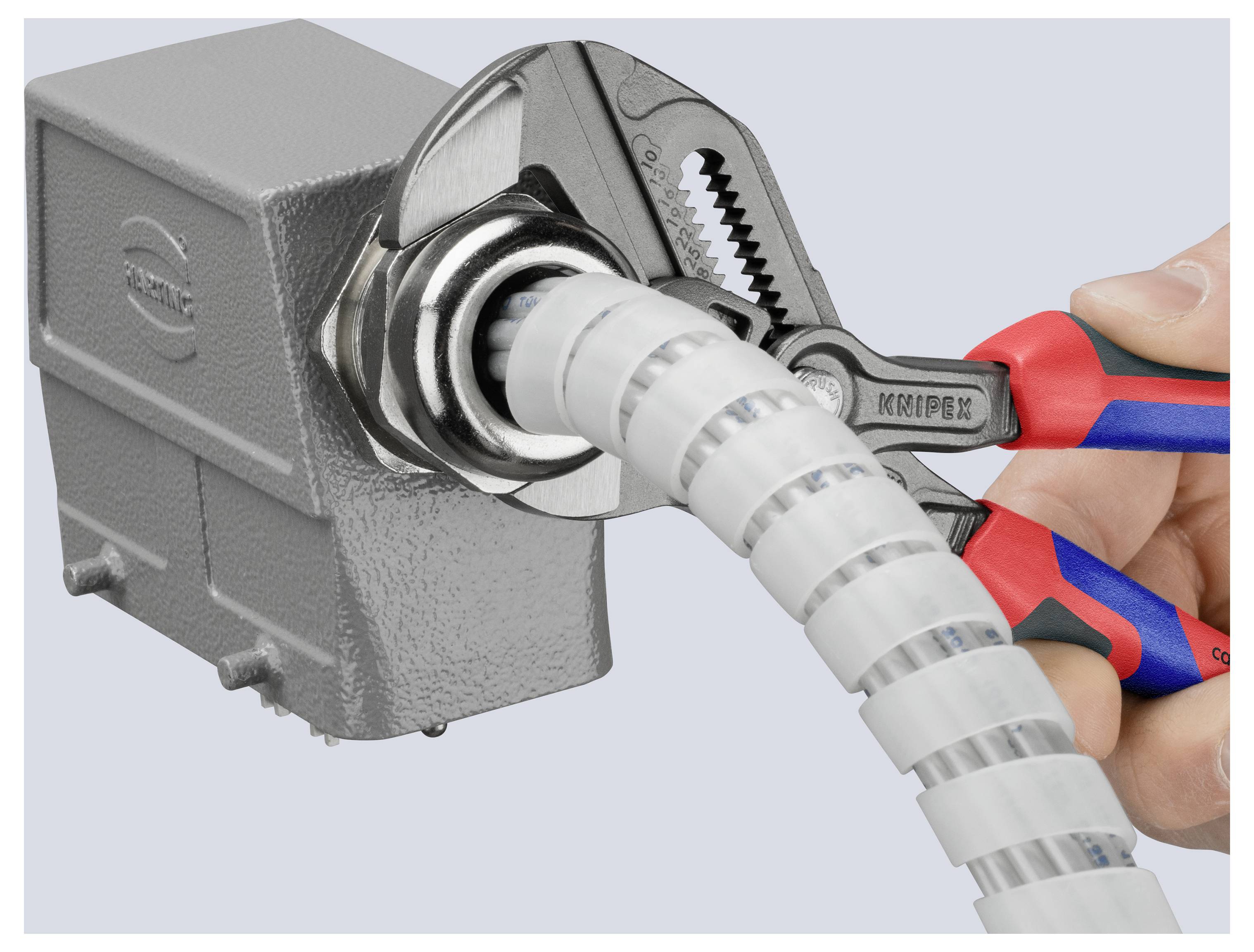 A wrench tightens a connector around a coiled conduit attached to an electrical box, demonstrating a secure installation method.