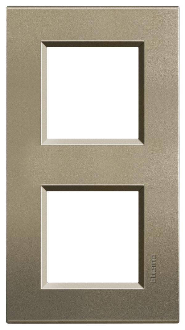 Double frame in bronze finish with two square cutouts for switches or sockets, simple, modern design.